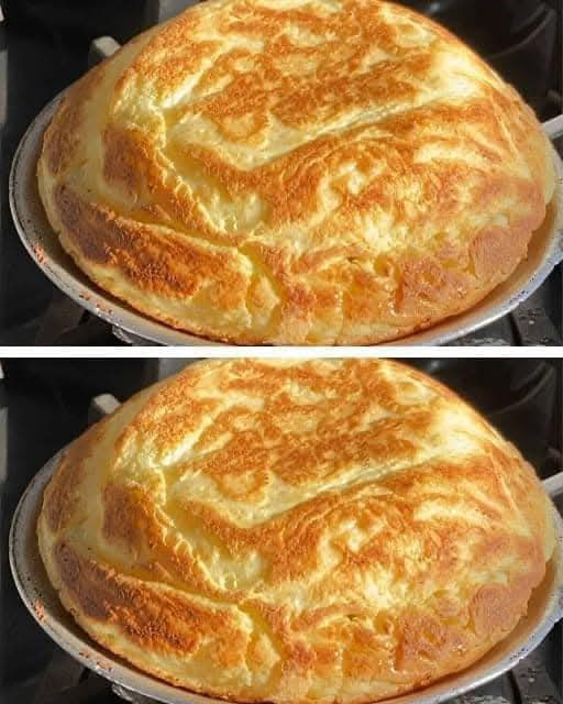 A fluffy, golden-brown soufflé omelette freshly cooked in a pan.